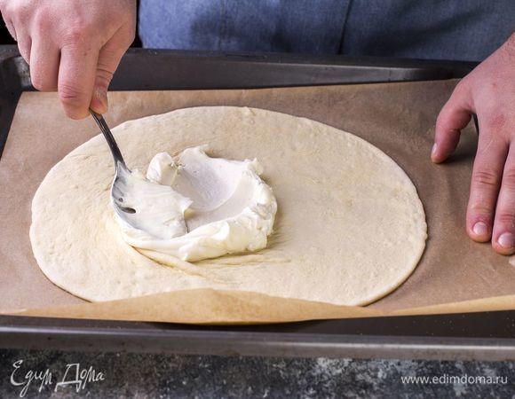 Раскатайте тесто в пласт, переложите на бумагу для выпечки. Основу для пиццы смажьте творожным сыром, смешанным с сахарной пудрой.