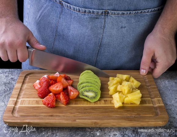 Разрежьте клубнику пополам, киви нарежьте кружочками, консервированные ананасы — дольками.