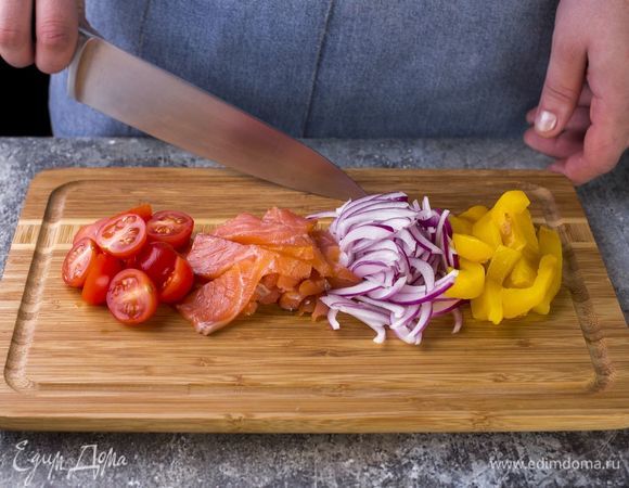 Нарежьте лук полукольцами, запеченный болгарский перец — небольшими полосками. Слабосоленного лосося нарежьте, помидоры черри разрежьте пополам.