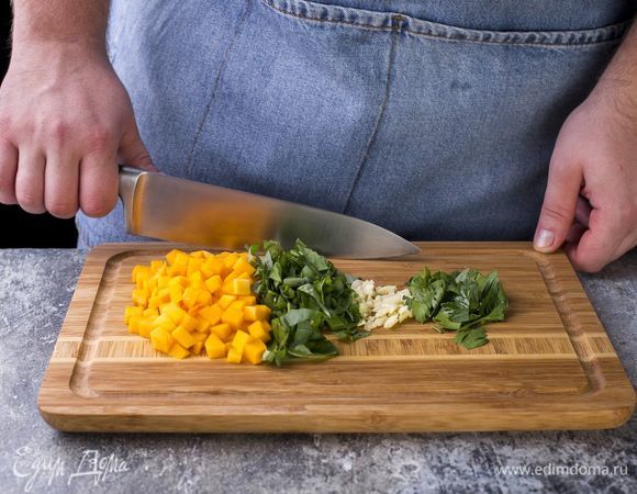 Тыкву нарежьте небольшими кубиками, измельчите чеснок, петрушку и базилик.
