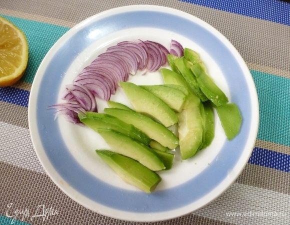 Авокадо нарезать ломтиками, сладкий лук — перьями. Полить все соком лимона.