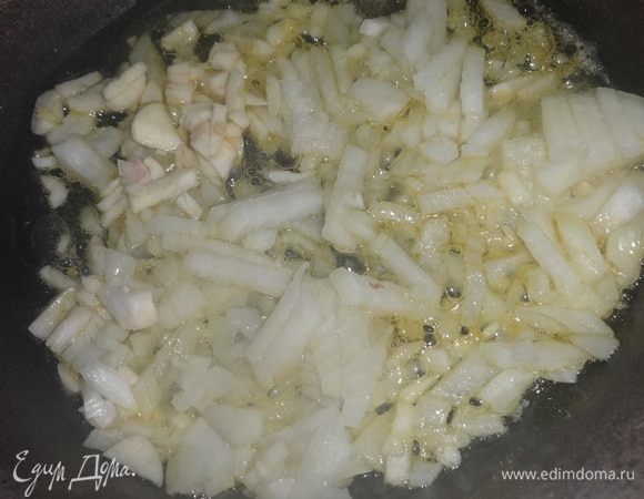 В сковороду налить половину нормы оливкового масла, разогреть. Всыпать лук и чеснок и обжарить на среднем огне, помешивая, в течение 5 минут.