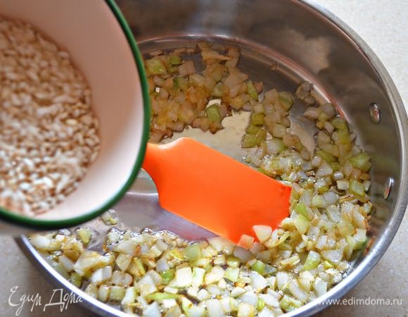 На оливковом масле обжарить чеснок (после этого его необходимо вынуть из сковороды, он больше не понадобится). Затем в сковороду добавить лук и слегка подрумянить. Далее в сковороду добавьте рис и обжаривайте, постоянно помешивая, 3 минуты. К рису влейте белое сухое вино и готовьте еще около 10 минут, пока вино не выпарится.