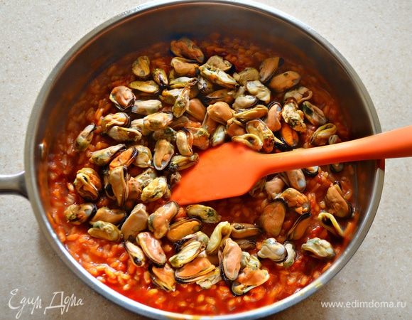 Как только рис станет снаружи мягким, а внутри останется слегка твердым, добавьте в сковороду хорошо промытые мидии и тушите 10 минут. Блюдо должно быть немного жидковатым. По окончании готовки накройте сковороду крышкой и оставьте на 10–15 минут.