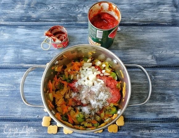 После этого добавляем томаты кусочками в собственном соку ТМ «Помидорка», а также баночку (70 г) томатной пасты того же производителя. Здесь уже дело ваших гастрономических пристрастий: можно и больше добавить, тогда соус приобретет более выраженный вкус помидоров. Также добавляем сахар, соль, черный молотый перец и ароматные травы, вливаем 200–250 мл воды. Перемешиваем.