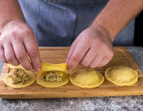 Возьмите тесто, посыпьте его мукой MAKFA для настоящих макарон и раскатайте в пласт толщиной 1–2 мм. Из теста вырежьте кружки. Положите в центр круга начинку, накройте сверху вторым кружком. Защипните края.