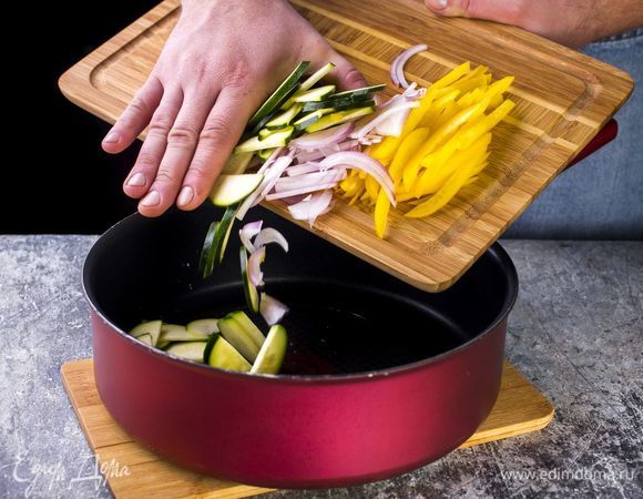 Цуккини нарежьте ломтиками, болгарский перец — соломкой, красный лук — полукольцами. Обжарьте овощи на оливковом масле в течение нескольких минут.