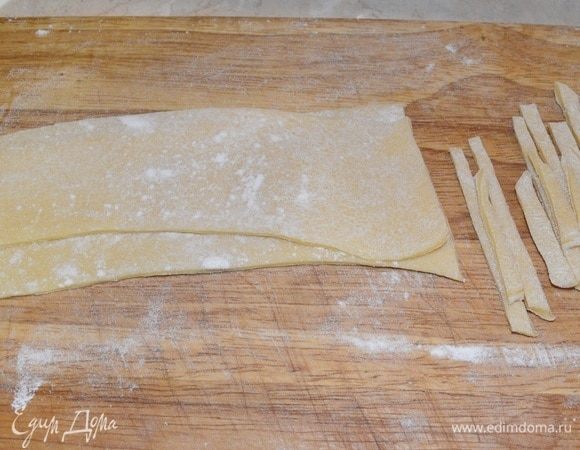 Две полоски кладем друг на друга и разрезаем. По необходимости посыпаем мукой рабочую поверхность, чтобы полоски не прилипали. Так же делаем с остальными 3 частями теста.