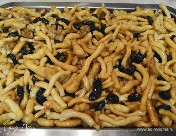 К чак-чаку добавить орехи, изюм, смешать. Добавить горячий сироп, перемешивать аккуратно. В форму, немного смазанную маслом, переложить чак-чак. Хорошо уложить в форме.