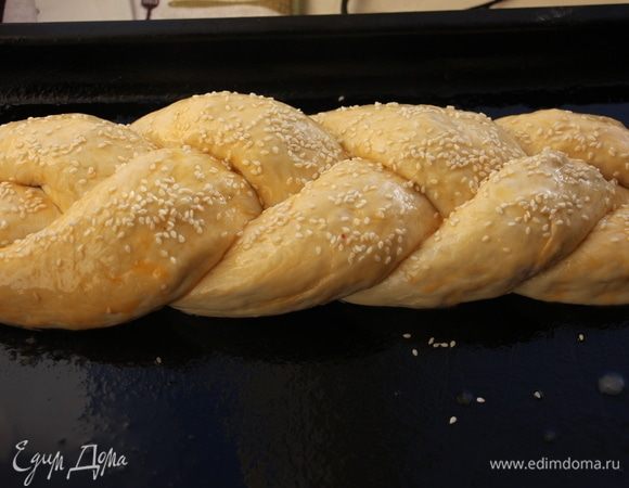 Сплести косичку из полосок теста. Верх можно смазать желтком или сладкой водой, посыпать кунжутом. Выпекать при температуре 180°C до золотистого цвета.