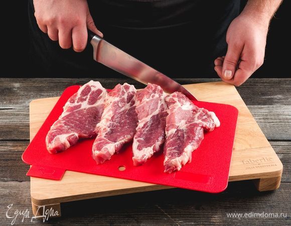 Нарежьте свинину крупными кусочками толщиной 1,5–2 см, используя разделочную доску Faberlic by Julia Vysotskaya. Натрите мясо солью и перцем.