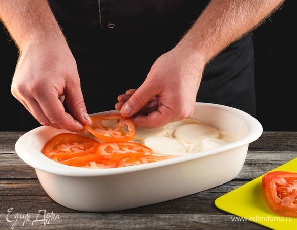 Выложите слой из колец лука и кружков помидора. Посыпьте сыром.