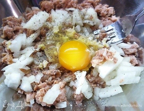 Добавляем в чашку к луку и рыбе яйцо, мелконарубленный зубчик чеснока, солим и перчим по вкусу, перемешиваем.