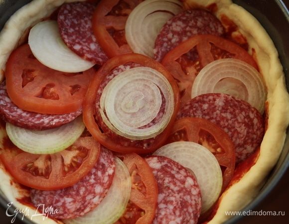Салями, лук, помидор нарезать слайсами и выложить, чередуя, на тесто.