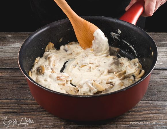 Залейте жареные грибы с луком сливочным соусом, потомите на слабом огне 2–3 минуты.