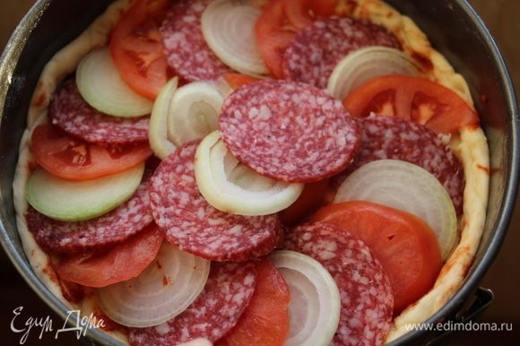 Раскатать вторую часть теста и выложить поверх начинки. Вторую часть теста также смазать томатной пастой ТМ «Помидорка» и выложить на нее салями, лук, помидор.