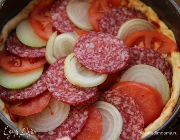 Раскатать вторую часть теста и выложить поверх начинки. Вторую часть теста также смазать томатной пастой ТМ «Помидорка» и выложить на нее салями, лук, помидор.