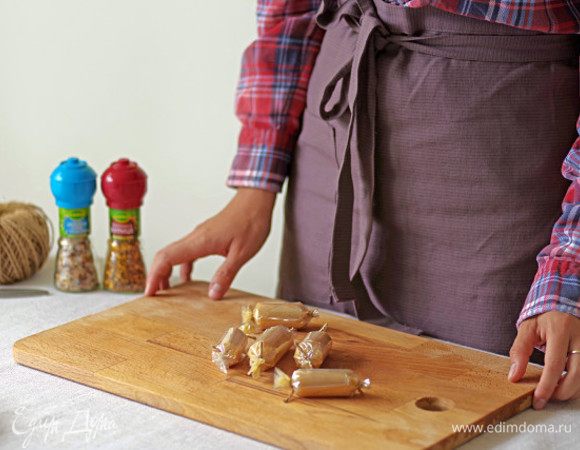 Выложите на середину каждого квадрата 2 ч. л. куриного фарша и заверните пленку трубочкой. Один конец завяжите ниткой, плотно утрамбуйте мясную смесь и завяжите второй конец трубочки.