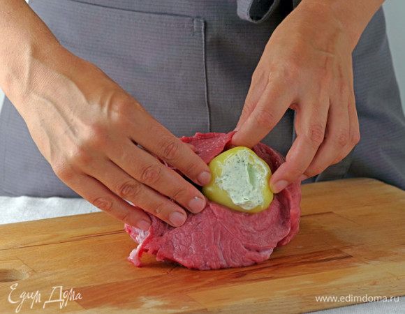 Разрежьте мясо вдоль почти до конца, слегка отбейте, положите в середину фаршированные перцы, оберните их говядиной, при необходимости замотайте рулет прочной ниткой.