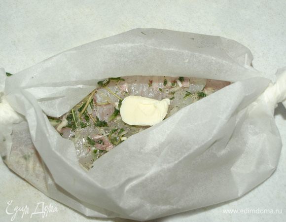 Заворачиваем пергамент лодочкой и кладем на рыбу сливочное масло (0,5 ч. л.).