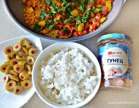 Рис промыть и отварить до готовности в подсоленной воде. Оливки (у меня — фаршированные перцем) нарезать кружочками. Тунец нарезать маленькими кусочками. Рис, оливки и тунец добавить к овощам и перемешать.