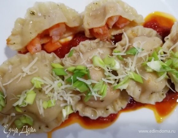 Выкладываем на тарелку соус, а сверху — равиоли. Украшаем сыром пармезан и зеленым луком.