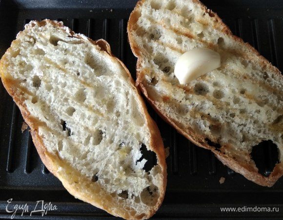 Натираем каждый ломтик разрезанным пополам зубчиком чеснока.