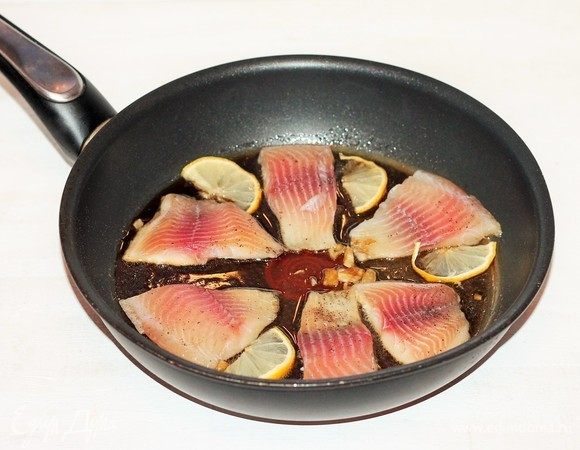 Разрезать филе рыбы на порционные кусочки и положить в соус. Обжарить кусочки рыбы с двух сторон до золотистого цвета так, чтобы рыбка не развалилась, кусочки были целые. Добавить лимонные дольки и разложить вокруг рыбки (добавляет более сильный лимонный вкус).