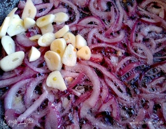 В глубокой сковороде обжариваем лук красный, нарезанный полукольцами, в течение 5 минут. Нарезаем чеснок и добавляем его к луку, обжариваем еще 5 минут.