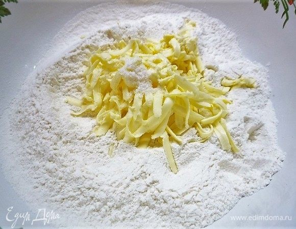 Для теста приготовим опару. Дрожжи и сахар насыпаем в небольшую миску, наливаем теплое молоко, перемешиваем и оставляем на 15–20 минут для активации дрожжей. В чашку насыпаем просеянную муку, добавляем натертое сливочное масло, соль, перетираем руками в крошку.