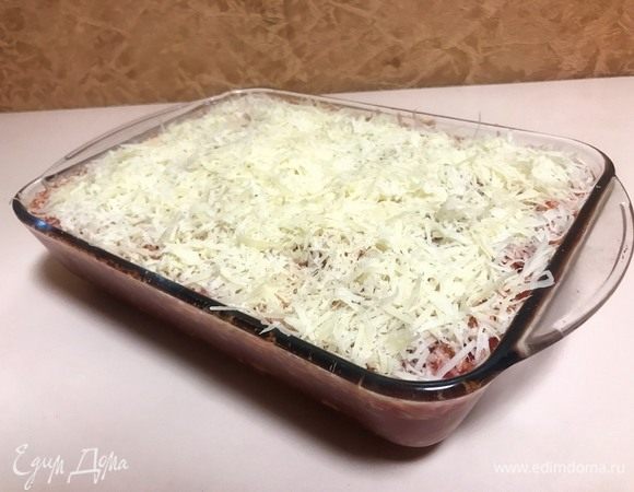 Посыпать блюдо тертым твердым сыром и поставить в разогретую до 200°C духовку на 45 минут.