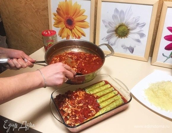 Смазать форму маслом и вылить 1/3 томатного соуса. Выложить фаршированные шпинатом и рикоттой каннеллони в форму для запекания сверху на соус. Желательно выкладывать трубочки в один слой, тогда они лучше пропитаются соусом и получатся вкуснее. Залить макаронные изделия оставшимся соусом.