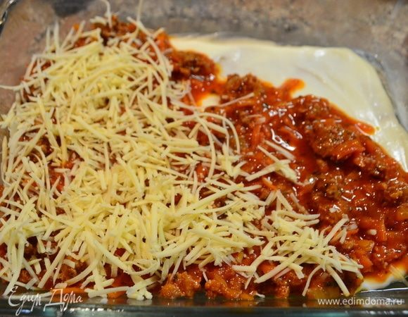 Начинаем собирать нашу лазанью. Форму смазать маслом, сначала выложить слой соуса бешамель, затем — листья пасты, снова соус бешамель, мясную начинку, сыр пармезан. Так повторяем несколько раз.