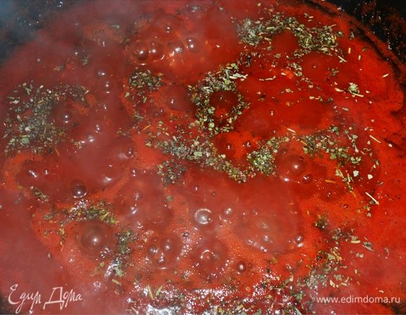 Затем измельчаем консервированные помидоры без кожи и добавляем вместе с соком к луку и чесноку. Приправляем по вкусу итальянскими сухими травами.