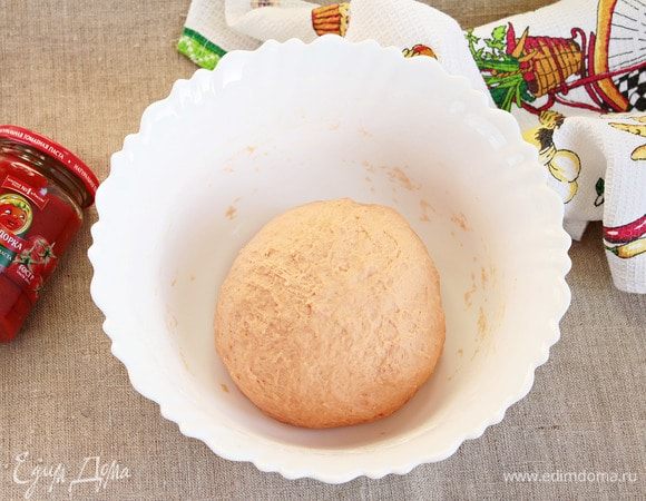 Муку пшеничную предварительно просеять. Всыпать сначала половину объема, вымешать, затем порционно добавить оставшуюся. Так как мука отличается по качеству, может потребоваться разное ее количество. Замесить крутое тесто. Добавить оливковое масло и месить, пока тесто не перестанет липнуть к рукам. Тесто станет эластичней. Укрыть миску с тестом пленкой и оставить в теплом месте для расстойки на 1,5–2 часа.