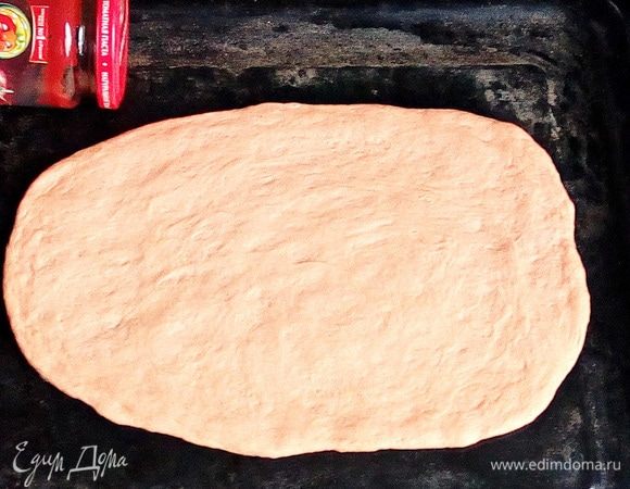 Раскатать овал из 1/4 части теста (можно руками сразу на противне) толщиной примерно 0,5–0,7 см.