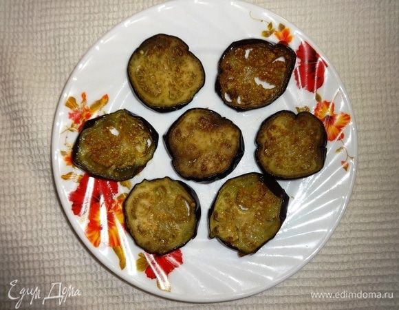 Собрать закуску. Для этого на тарелку выложить часть кружков баклажанов.