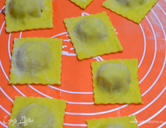 Далее начинку выкладываем на раскатанный пласт теста горками, смазываем промежутки желтком или водой с помощью кисточки, накрываем другим пластом теста и формируем равиоли, по краям проходимся вилкой или специальным кругом. Форма у равиоли может быть совершенно разной: квадратной, круглой, треугольной и т. д.