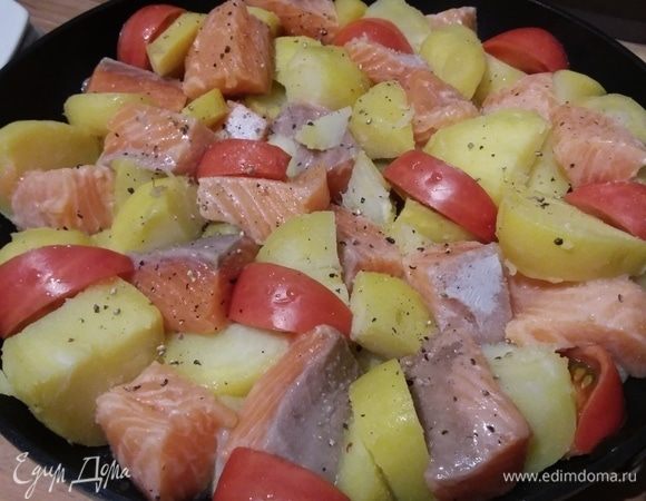 Картофель и лосося сложить в форму, в которой они будут запекаться. Между кусочками картофеля и лосося выложить половинки черри или дольки более крупных помидоров.