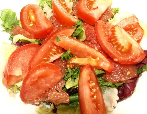 Помидор нарезать дольками, предварительно удалив плодоножку. Выкладываем на грейпфрут. Поливаем оставшейся заправкой.