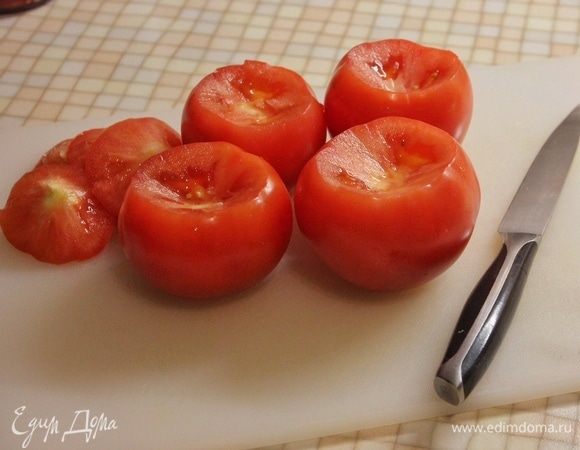 Под небольшим углом срезаем шляпки у помидоров. Аккуратно ложкой вынимаем мякоть, не повреждая стенки. Мякоть выкладываем в отдельную посуду.