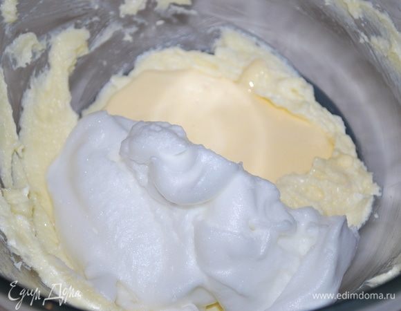 В миску добавляем половину взбитого масла с сахаром, половину яичных белков с сахаром и половину яичных желтков с сахаром. Смешиваем лопаткой снизу вверх. И так в два приема добавляем все три массы, перемешиваем лопаткой аккуратно снизу вверх.