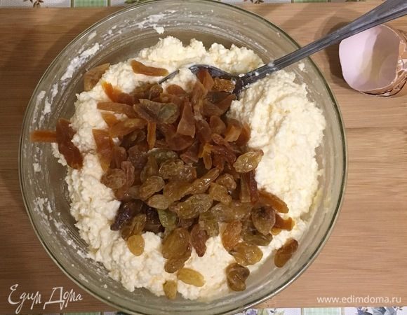 Добавьте нарезанную кубиками курагу и изюм. Выложите творожную массу в предварительно смазанную маслом и посыпанную тонким слоем манки форму.