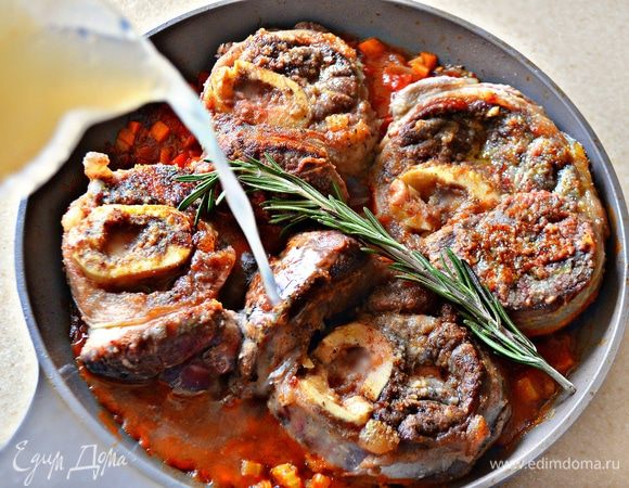 Далее на овощную подушку выложите обжаренные стейки мяса, влейте мясной бульон (у меня остался от варки кролика), сверху положите веточку розмарина, накройте крышкой и тушите 2 часа.