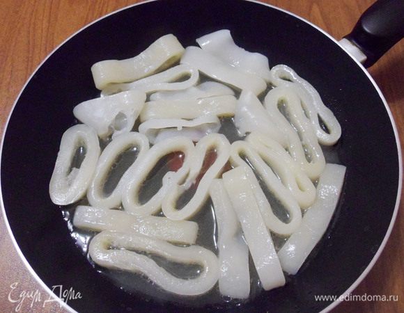 Убрать чеснок, выложить нарезанные кальмары, увеличить огонь до максимума.