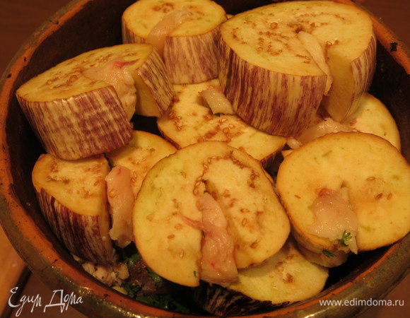 На мясо кладем баклажаны, сверху — лук, заливаем стаканом воды, ставим на 1,5 часа в духовку при 200°C (до полуготовности).