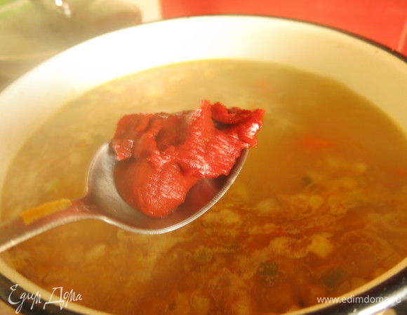 Кладем 1–2 ложки томатной пасты в рассольник, солим, перчим.