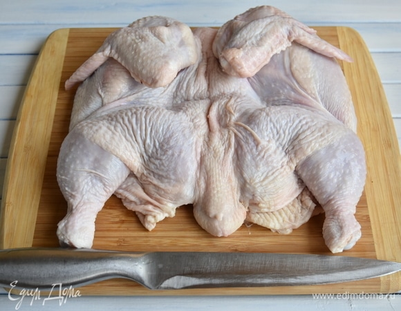 Острым ножом разрезать цыпленка вдоль по грудке и развернуть тушку, как книжку. Со стороны хребта слегка придавить руками и развернуть края тушки, выворачивая ее со стороны суставов наружу.