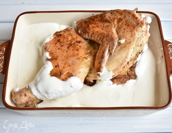 Обжаренного цыпленка выложить в форму для запекания и залить соусом из сметаны и чеснока. Можно дополнительно добавить в соус специи. Если сметана слишком густая, можно добавить немного воды. Запекать блюдо в духовке, разогретой до 180°C, 20–25 минут. Подавать, посыпав рубленой зеленью. Оставшийся соус можно слить в соусник и также подать к столу.