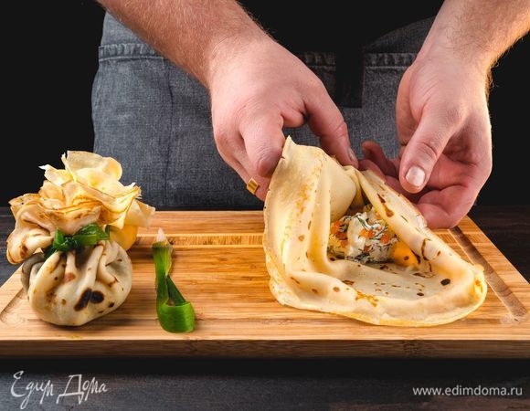 Выложите начинку в центр блина. Сверните блин в виде мешочка, верхушку завяжите зеленью.